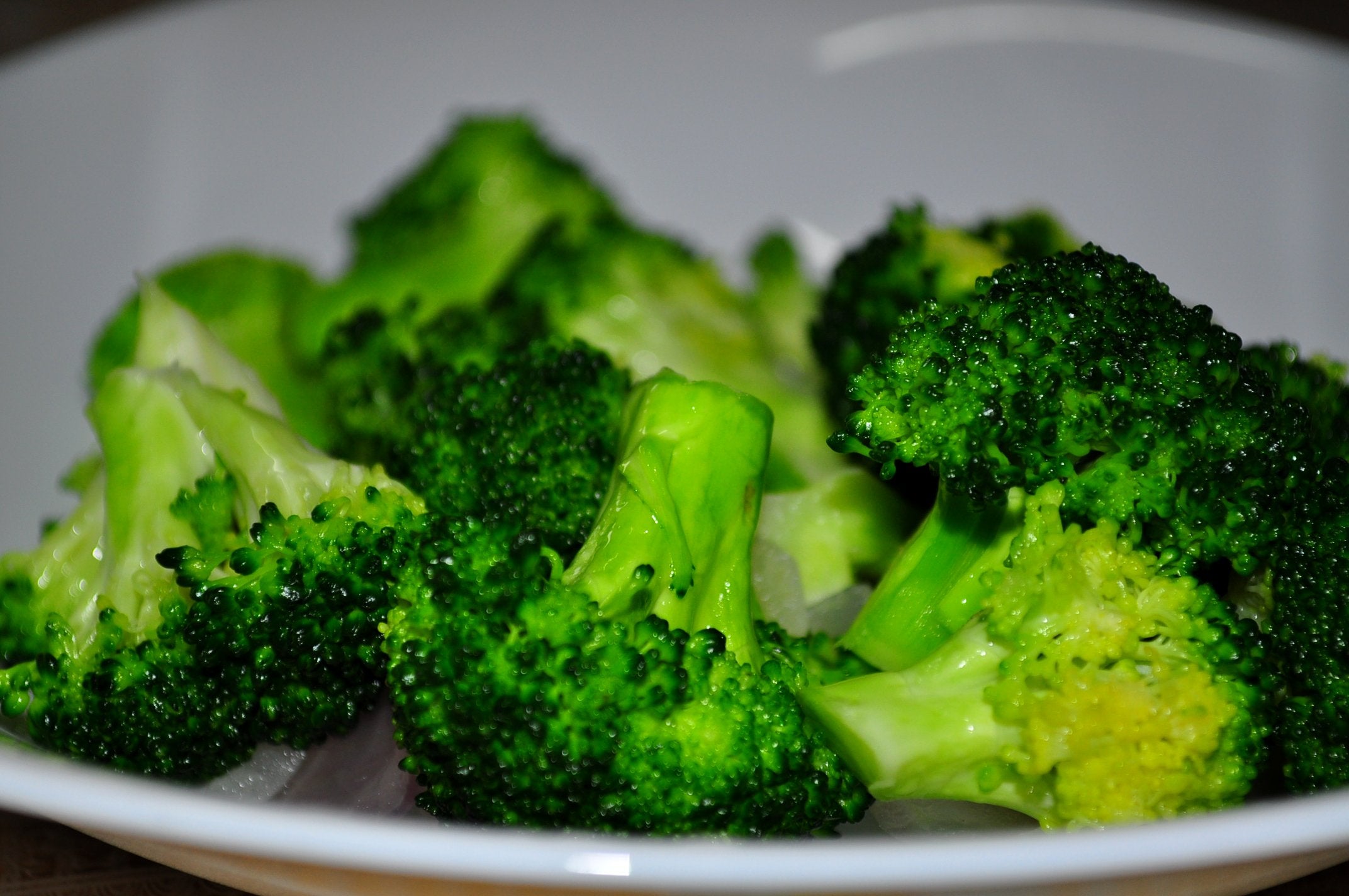 A white plate filled with several pieces of cooked broccoli florets.