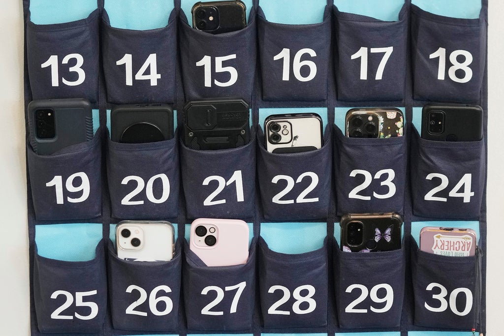 A wall organizer with numbered pockets holds various smartphones and one labeled card, occupying pockets numbered 13 to 31.