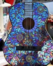 A guitar decorated with a colorful mosaic pattern of blue, purple, and multicolored tiles.