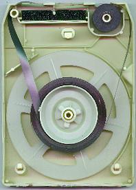 An open view of a magnetic tape data cartridge showing the internal spool of tape and winding mechanism inside a plastic casing.