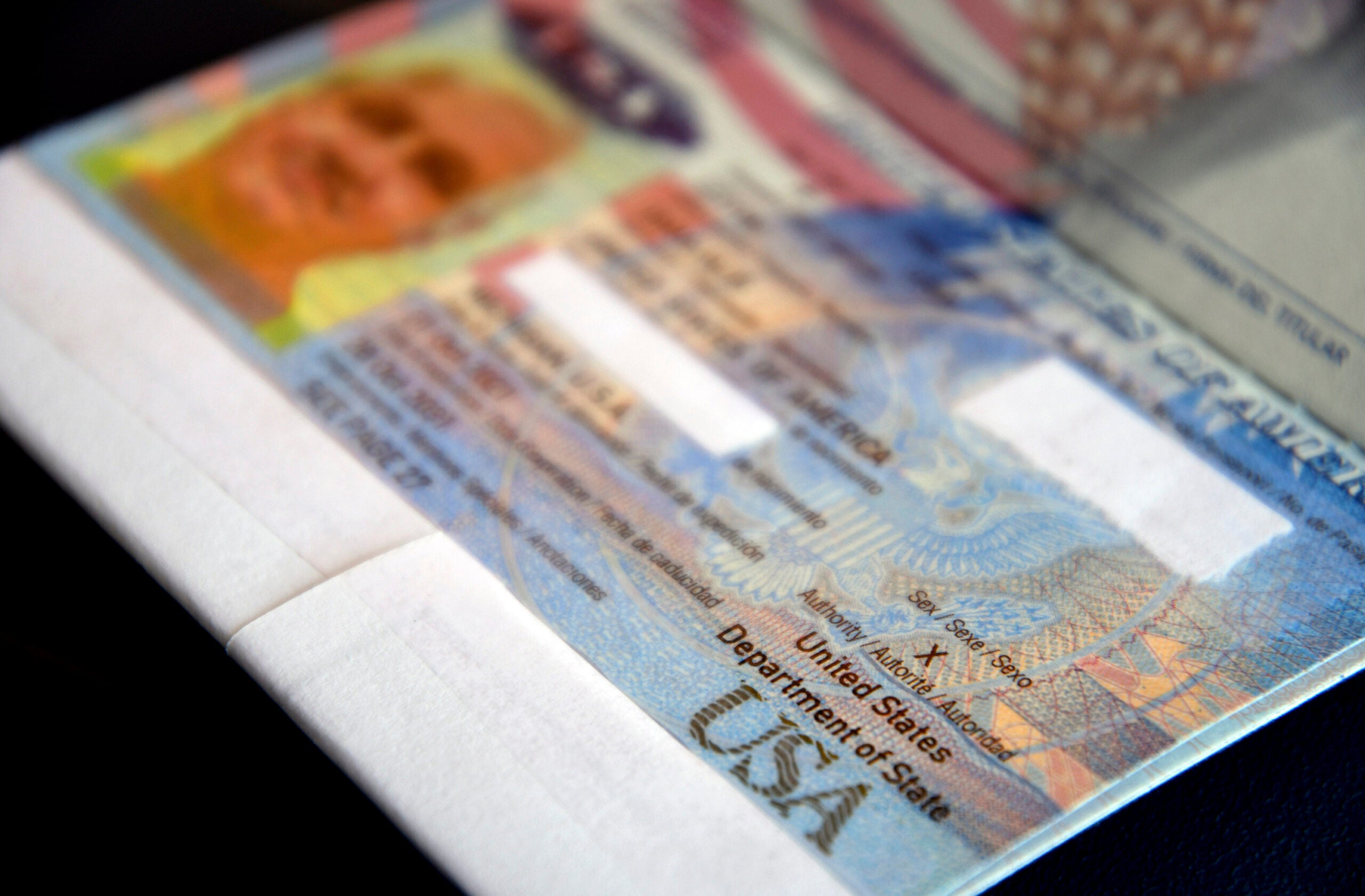 Close-up of a U.S. visa page in a passport, showing security features, the U.S. Department of State seal, and partially blurred personal information.