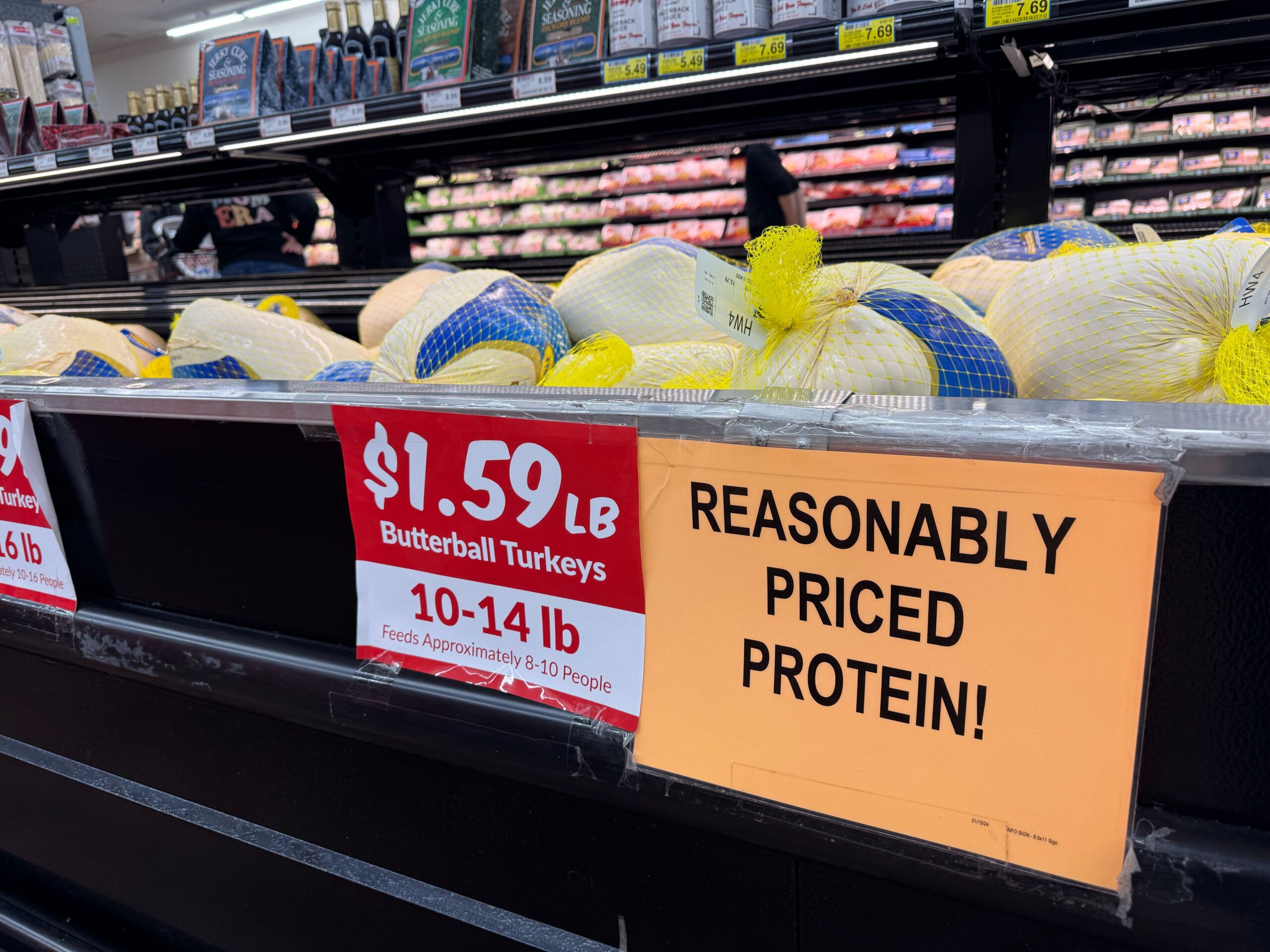 Display of Butterball turkeys priced at $1.59 per pound with a sign reading REASONABLY PRICED PROTEIN! in a grocery store meat section.