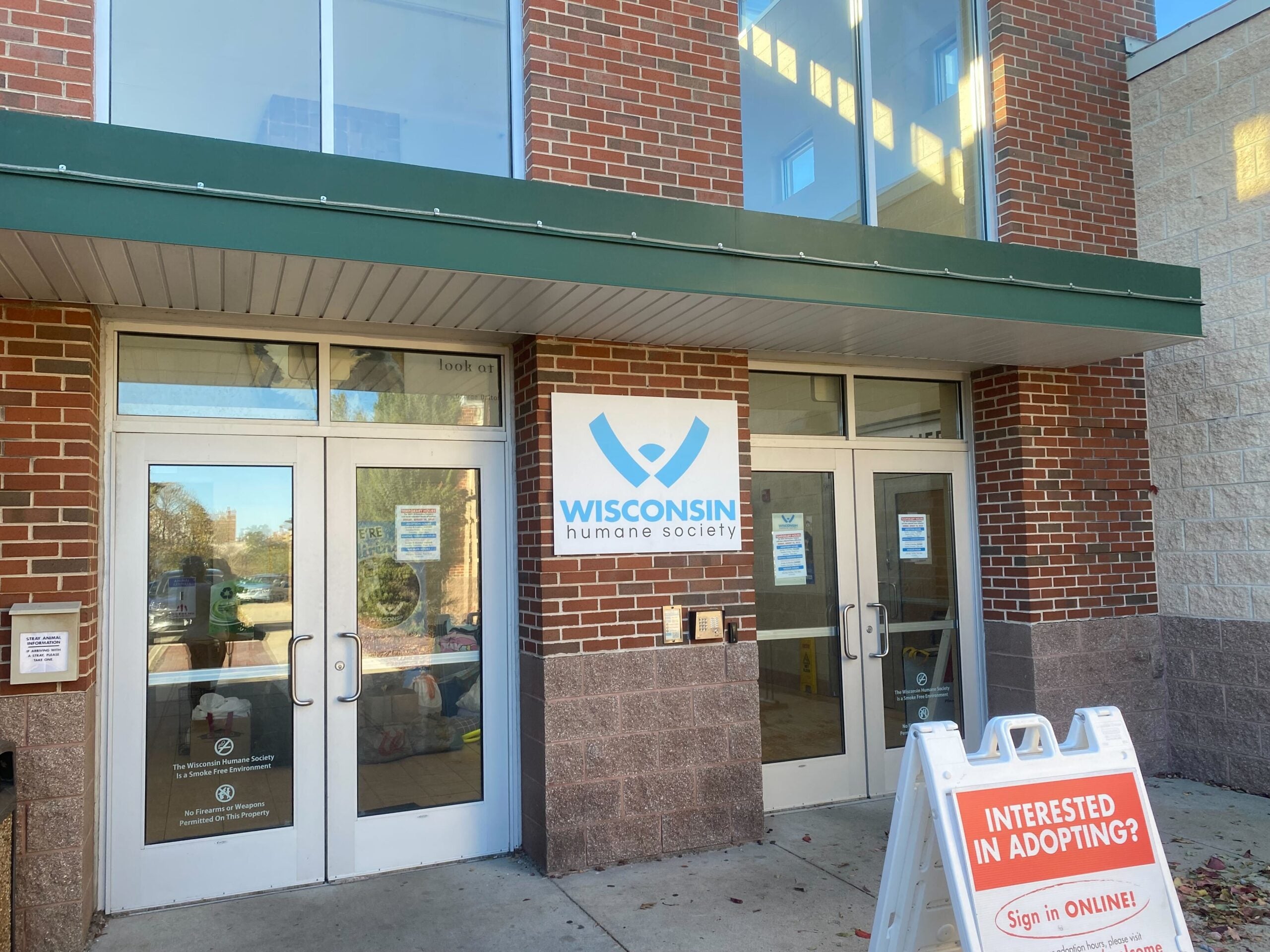 Entrance to the Wisconsin Humane Society building with a signboard outside inviting visitors interested in adopting animals.