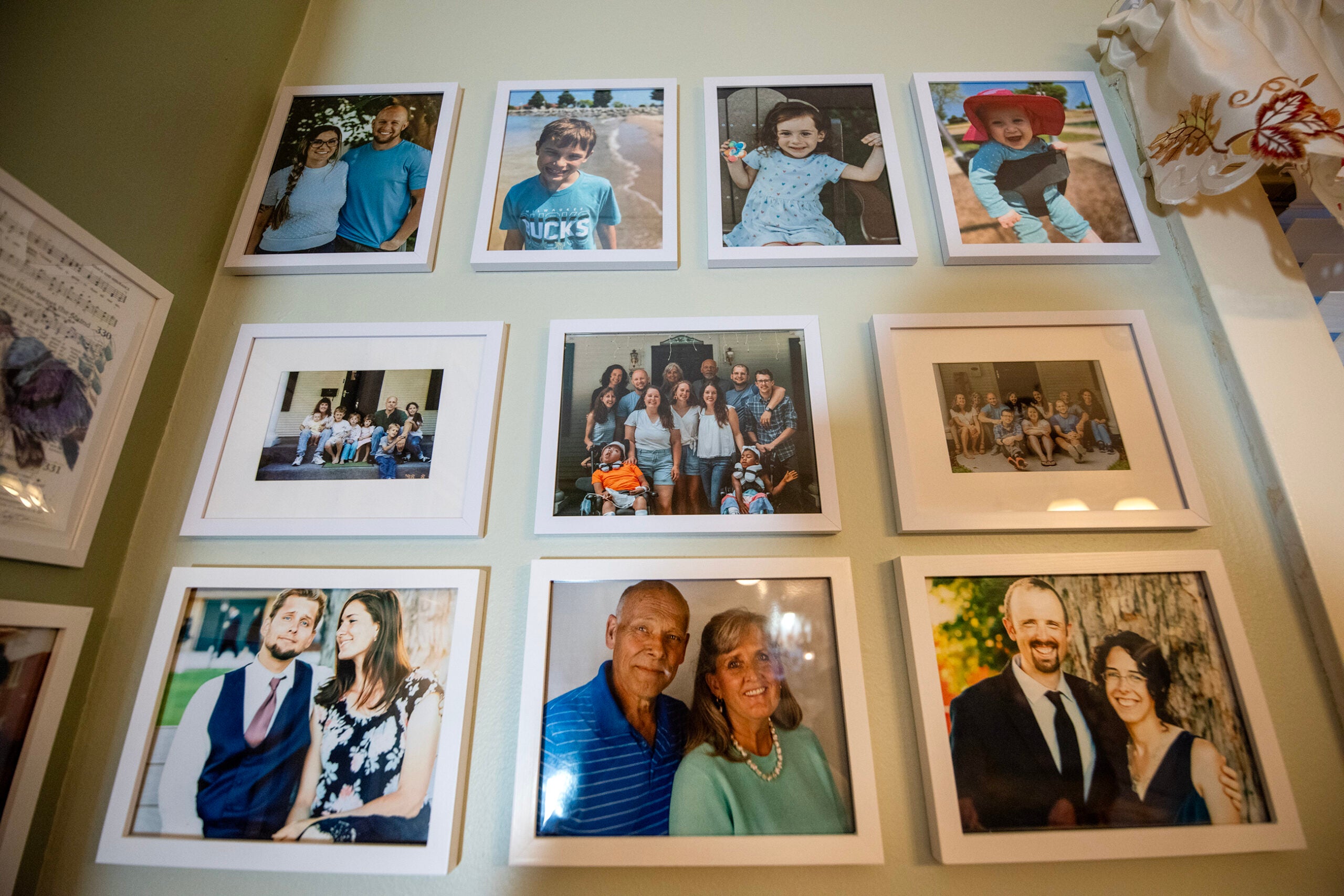 A wall displays nine framed family photographs arranged in three rows, featuring group and individual portraits of adults and children.