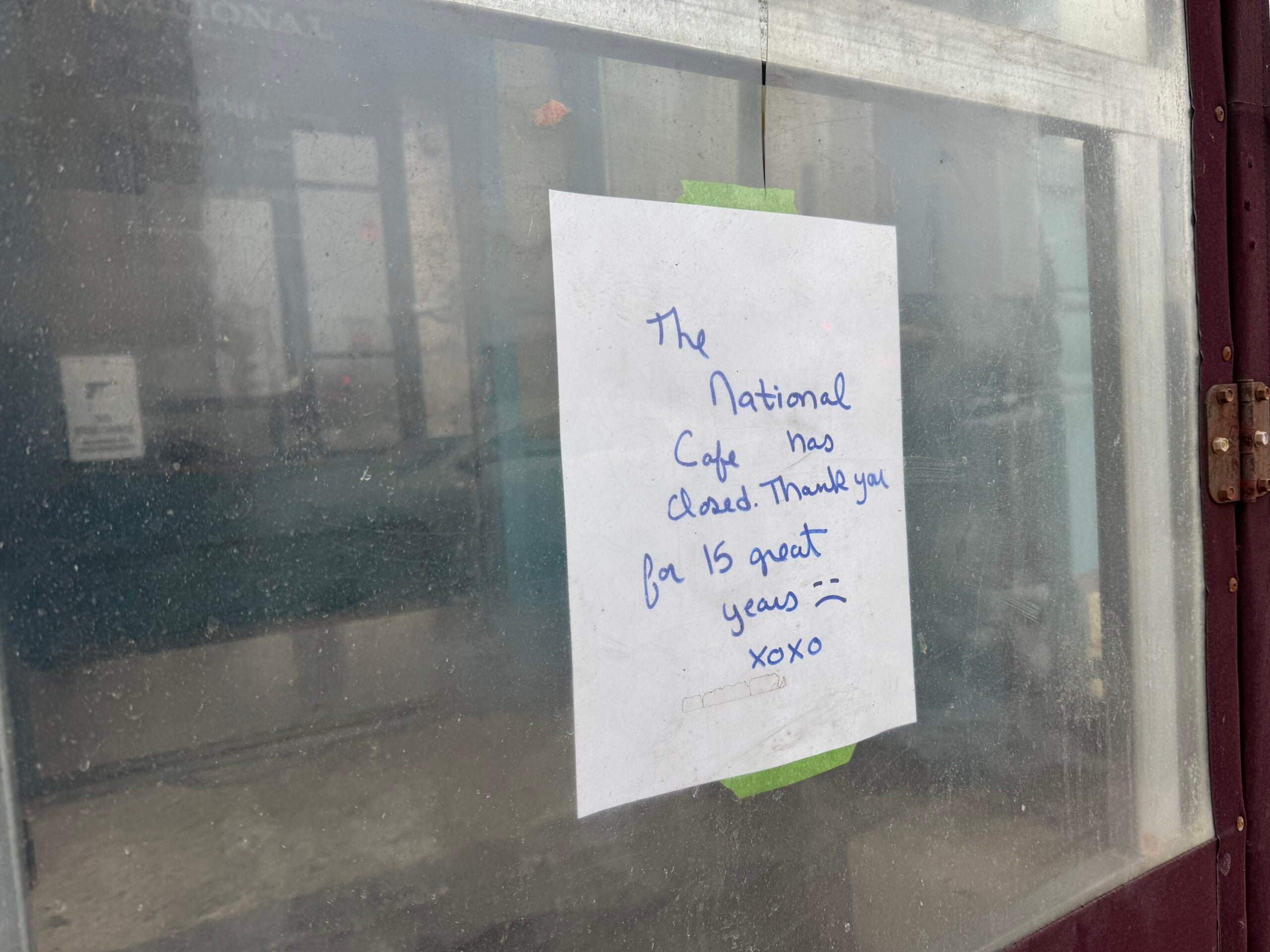 A handwritten sign taped to a glass door reads, The National Cafe has closed. Thank you for 15 great years! xoxo.