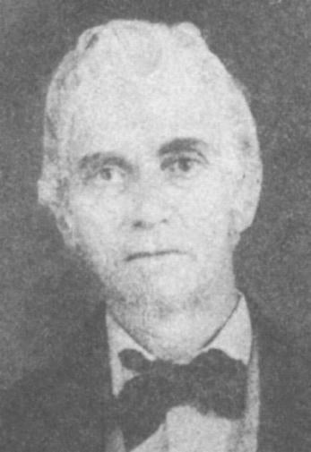 Black and white portrait of an older man with light hair, wearing a dark suit, white shirt, and a bow tie, looking directly at the camera.